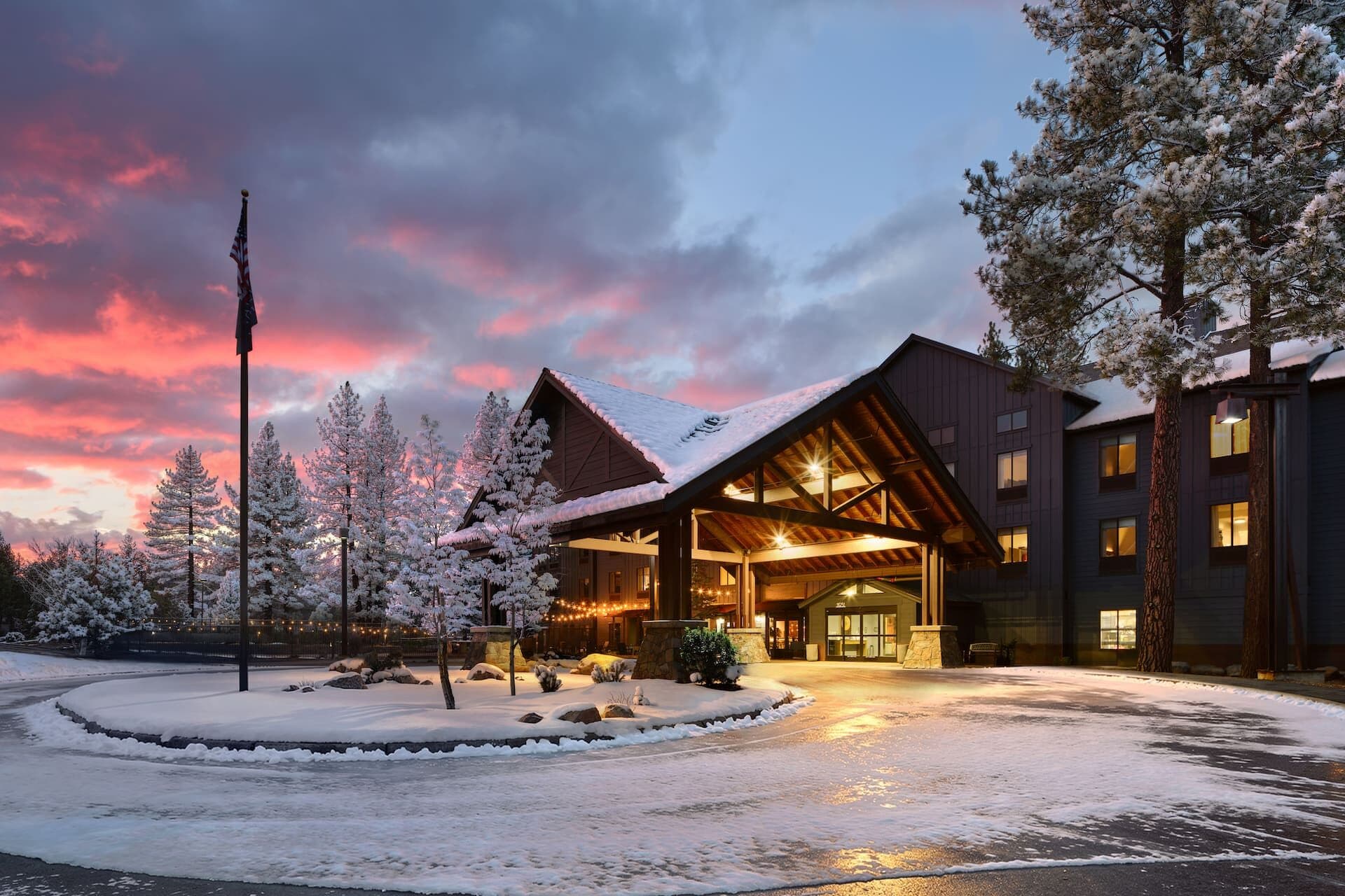 Martis Valley Lodge (formerly Hampton Inn Truckee) — mountain lodge exterior at dusk with snow and warm illuminated windows, Truckee CA Martis Valley Lodge (formerly Hampton Inn Truckee) — mountain lodge exterior at dusk with snow and warm illuminated windows, Truckee CA