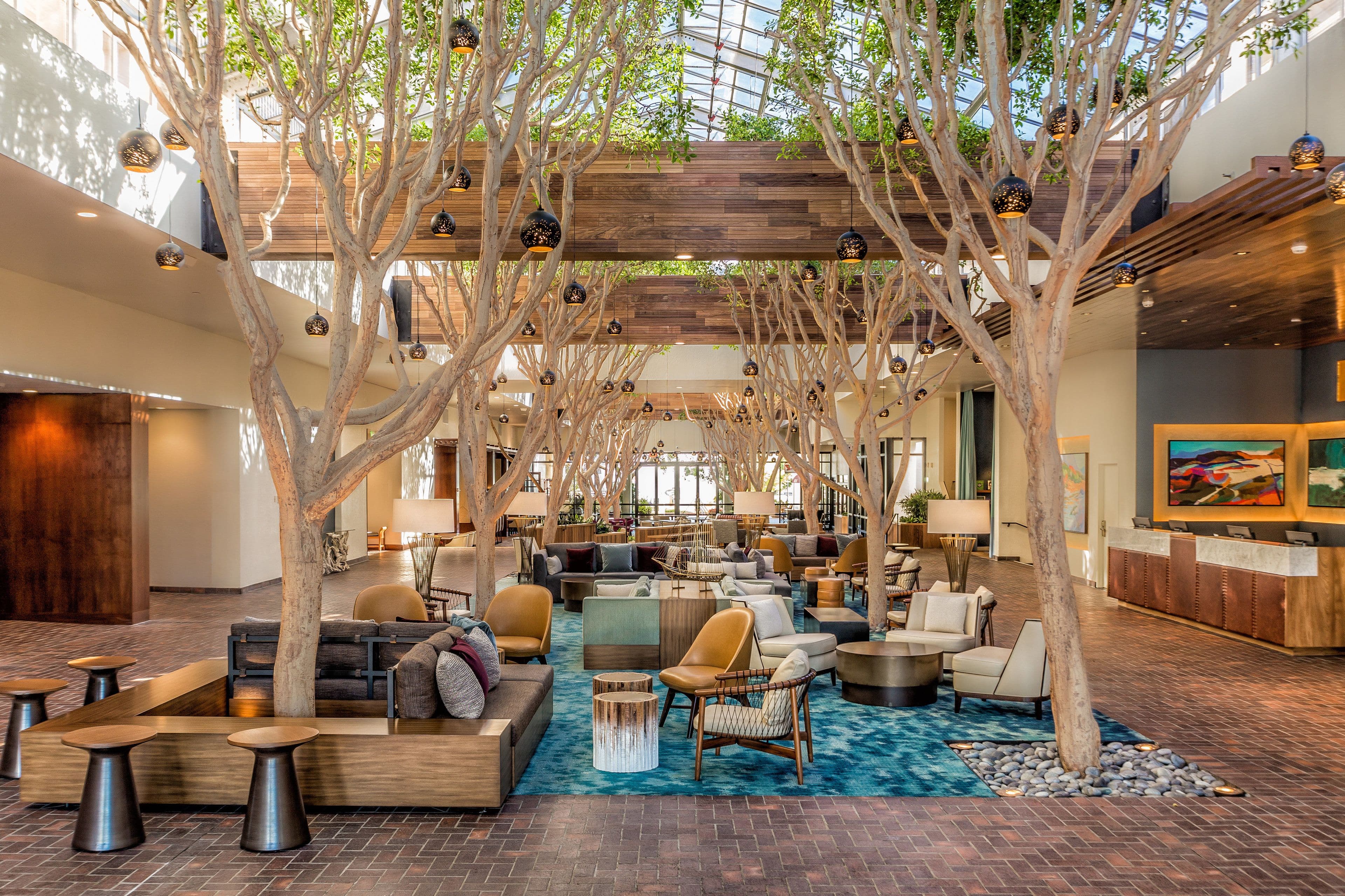 Portola Hotel & Spa Monterey Bay open lobby with indoor trees and modern furnishings Portola Hotel & Spa Monterey Bay open lobby with indoor trees and modern furnishings